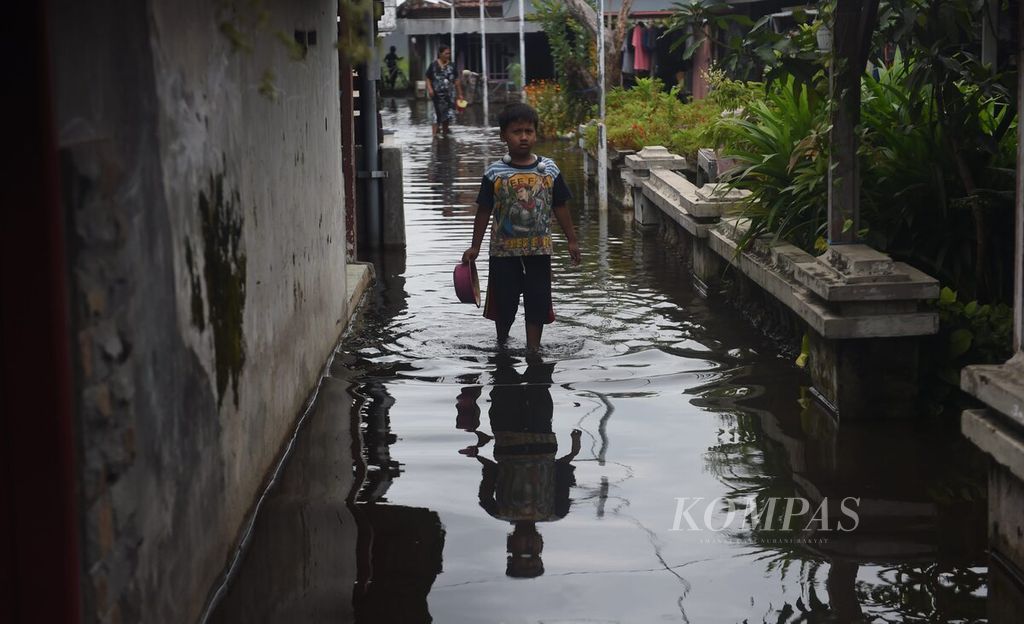 Anak melintasi gang yang tergenang banjir di Desa Kedung Banteng, Kecamatan Tanggulangin, Kabupaten Sidoarjo, Jawa Timur, Rabu (1/2/2023). 