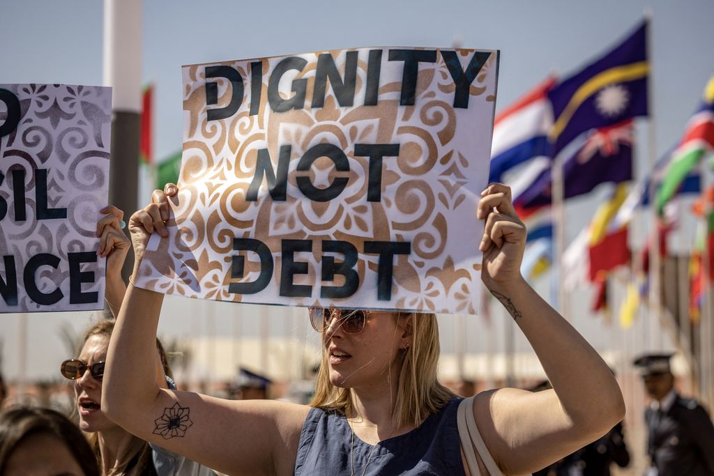 Aktivis memegang poster saat unjuk rasa menentang kemiskinan dan perubahan iklim pada hari pertama pertemuan tahunan Dana Moneter Internasional (IMF) dan Bank Dunia di Marrakesh, Maroko, 9 Oktober 2023.