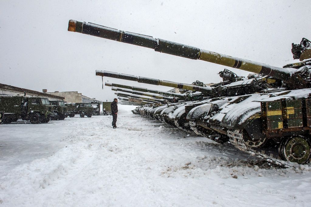 Seorang anggota militer Ukraina berdiri di depan sederetan tank dari Batalion 92 di Klugino-Bashkirivka, di dekat wilayah Kharkiv, Senin (31/1/2022).