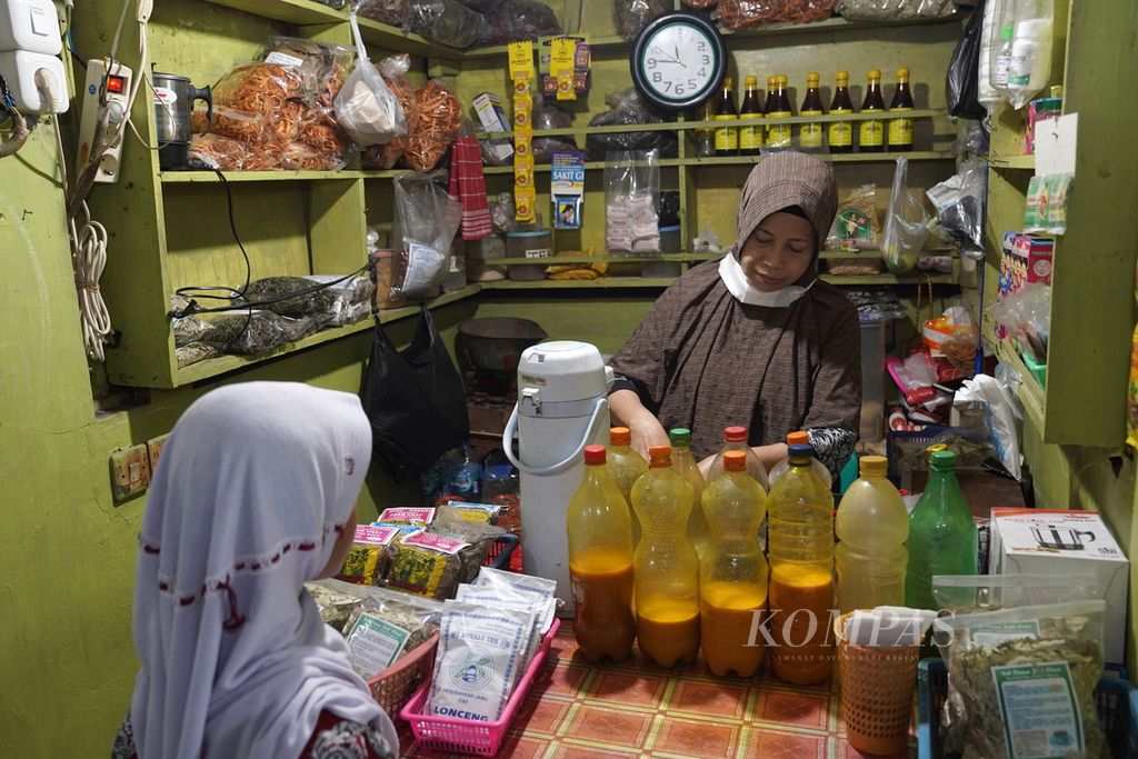 Ibu Dwi melayani pembeli di toko jamu Sido Waras di Pasar Perumnas Klender, Jakarta Timur, Selasa (12/12/2023).