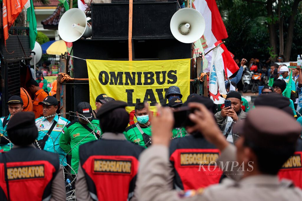 Spanduk bertuliskan <i>omnibus law </i>yang dipasang pada salah satu kendaraan saat peringatan Hari Buruh Internasional di depan Kantor DPRD Jawa Tengah, Kota Semarang, Senin (1/4/2023).