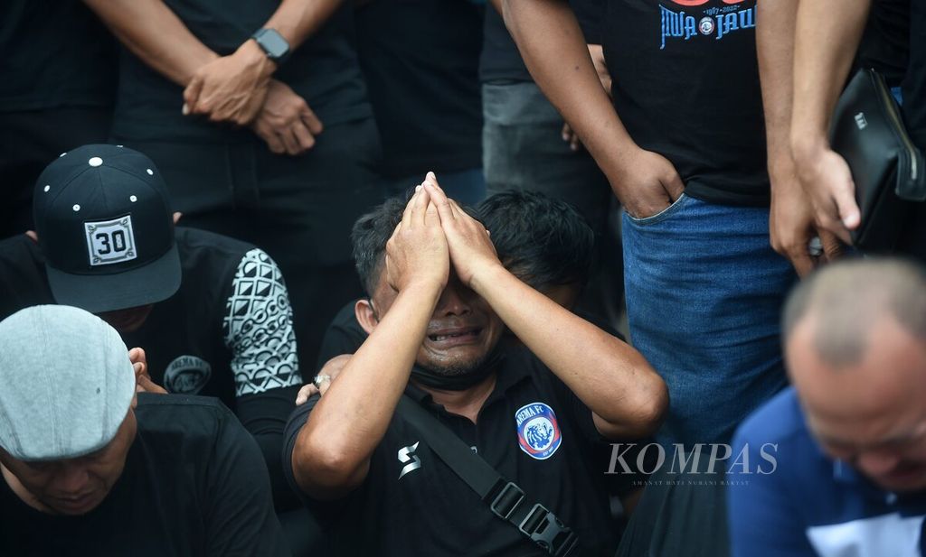 Ofisial Arema FC menangis saat memberikan penghormatan bagi korban yang meninggal dalam kerusuhan di Stadion Kanjuruhan, Kabupaten Malang, Jawa Timur, Senin (3/10/2022).