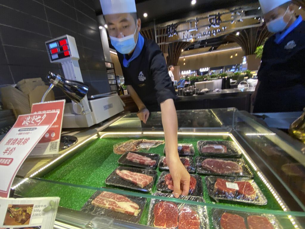 Pekerja menempelkan label pada produk daging sapi yang didiskon di pujasera di Beijing, 28 Agustus 2020. China menghentikan impor daging sapi dari Australia dengan alasan obat terlarang di dalam daging. 