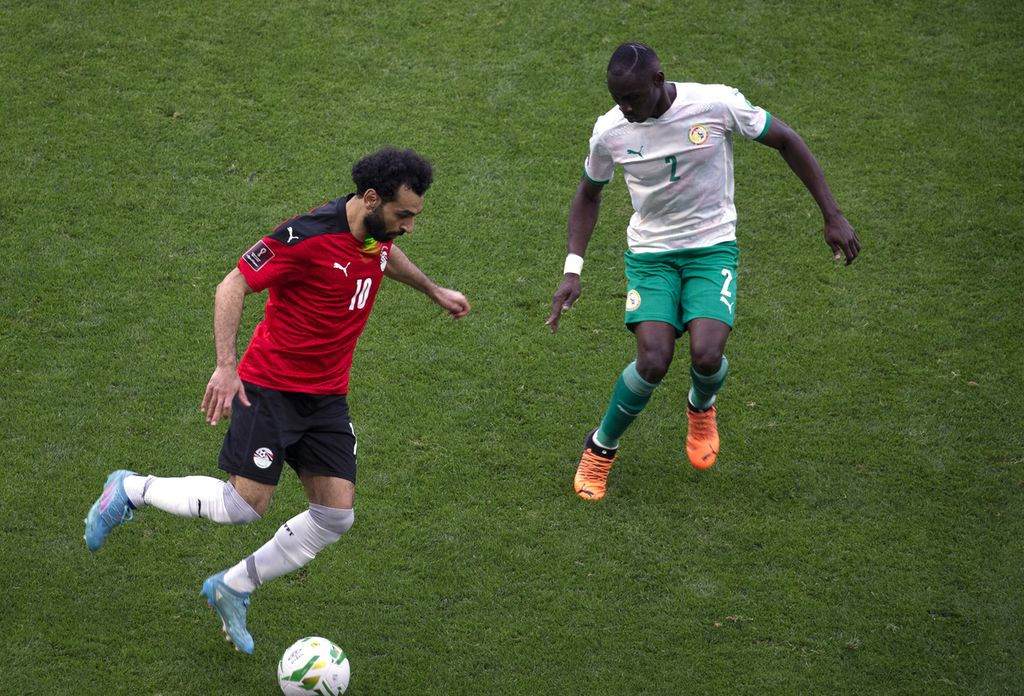 Pemain Mesir, Mohamed Salah (kiri), mengontrol bola di depan pemain Senegal, Saliou Ciss, pada pertandingan kualifikasi Piala Dunia 2022 antara Senegal dan Mesir di Stadion Abdoulaye Wade, Dakar, Senegal, Rabu (30/3/2022) dini hari WIB. 