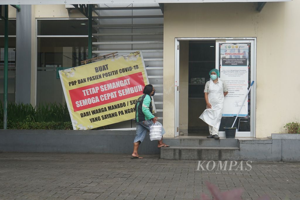Pengojek daring membawa pesanan makanan melalui pintu samping Instalasi Gawat Darurat RSUP Kandou, Manado, Sulawesi Utara, Selasa (1/12/2020). RSUP Kandou yang menjadi rumah sakit rujukan utama untuk Covid-19 disebut tak dapat menampung lagi pasien di ruang isolasi.