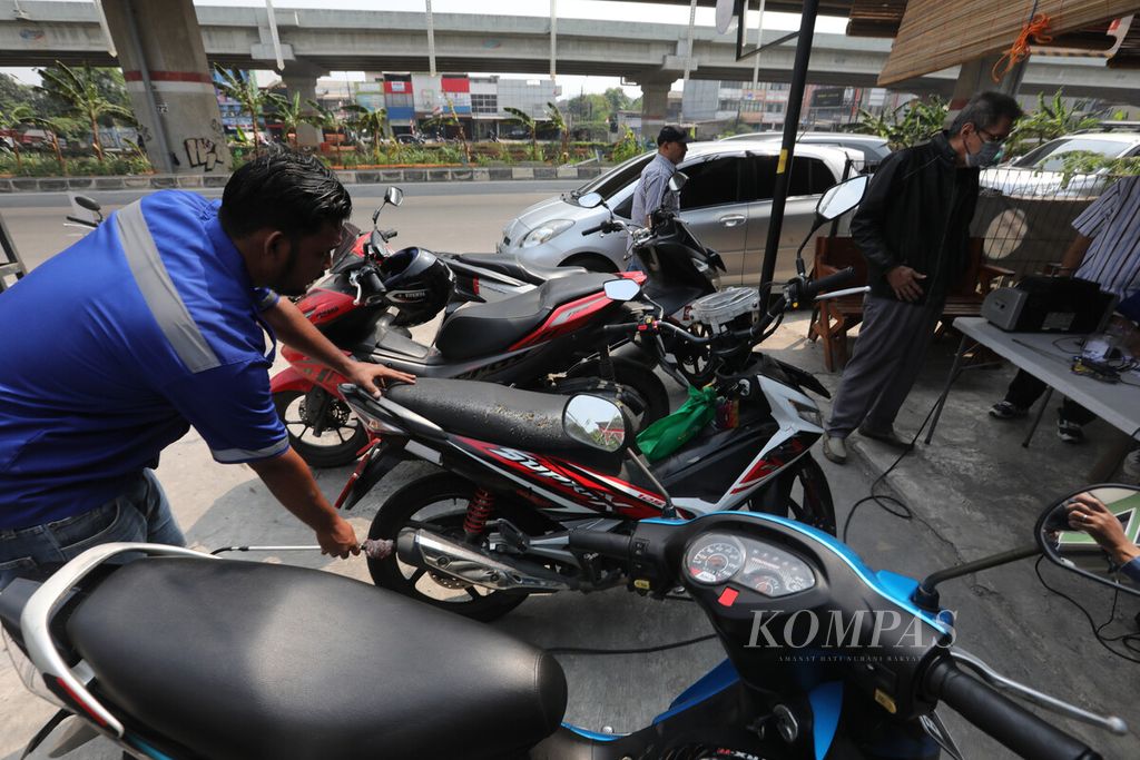 Petugas menguji emisi sepeda motor di kios pengujian di kawasan Lampiri, Duren Sawit, Jakarta Timur, Selasa (29/8/2023). 
