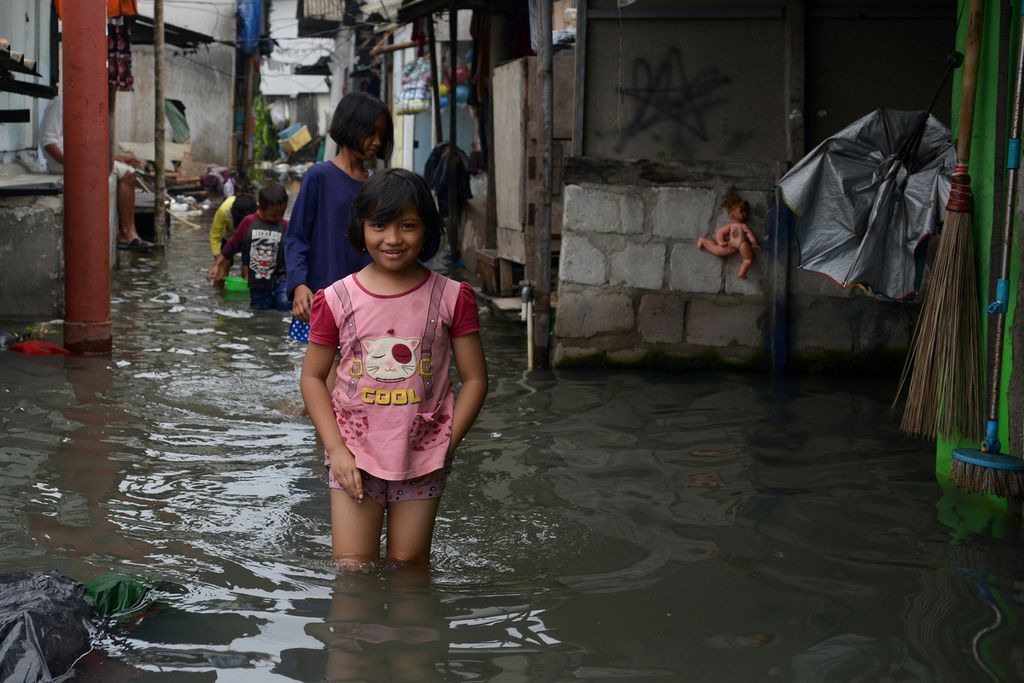 Sejumlah anak berjalan di tengah genangan banjir rob di Blok Empang, Penjaringan, Jakarta Utara, Senin (26/12/2022). 