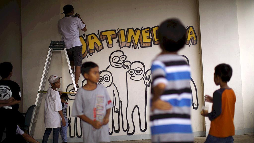 Seniman mural Riyan Riyadi, pembuat karakter bernama The Popo, beraksi di Rusunawa Jatinegara Barat, Jakarta Timur, pertengahan Maret lalu. Puluhan seniman mural Jakarta mengaktifkan 50 ruang publik terpadu ramah anak dengan pelatihan seni grafiti bersama remaja dan menggambar bersama di ruang publik tersebut.