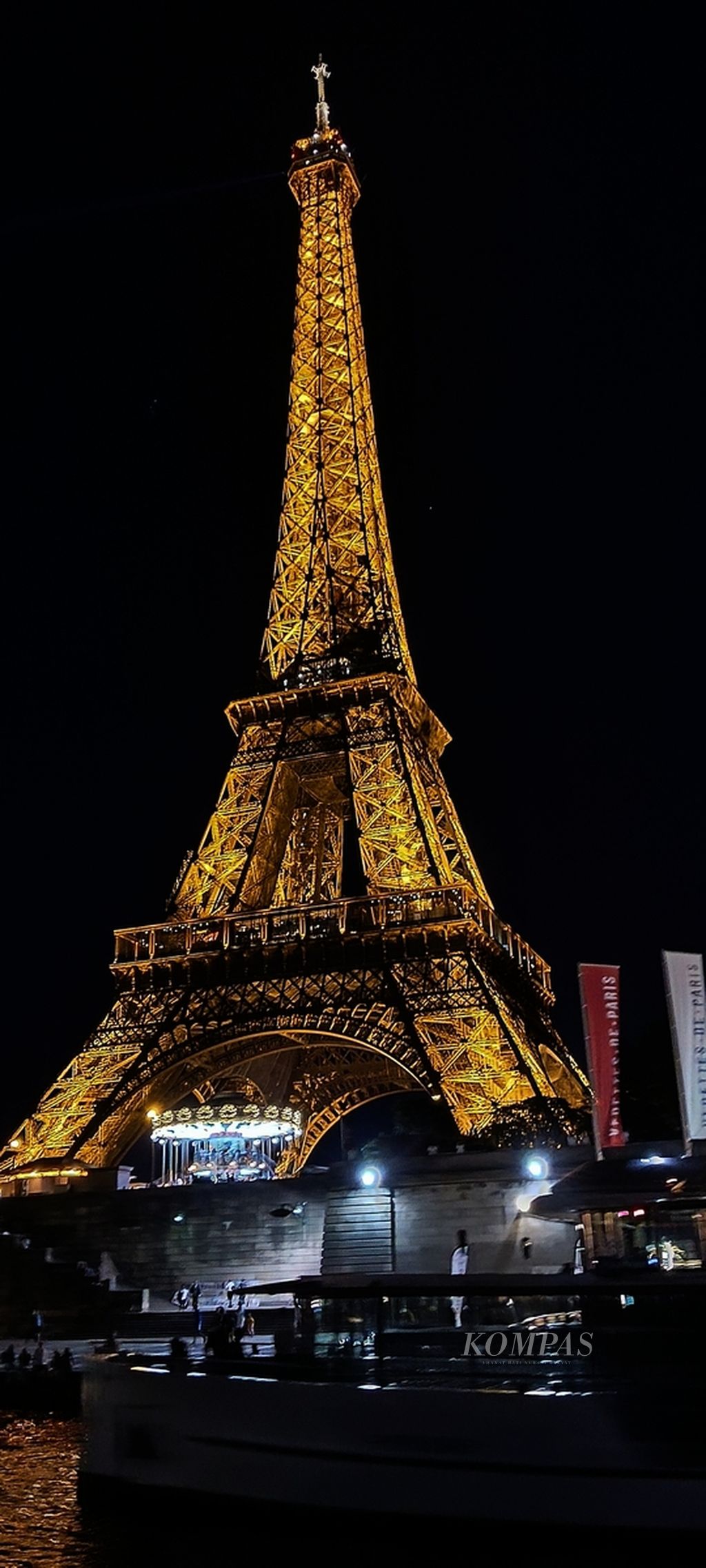 Gemerlap cahaya lampu Menara Eiffel yang terlihat dari perahu wisata Bateau Parisien yang membawa wisatawan menyusuri Sungai Seine, Selasa (18/7/2023).