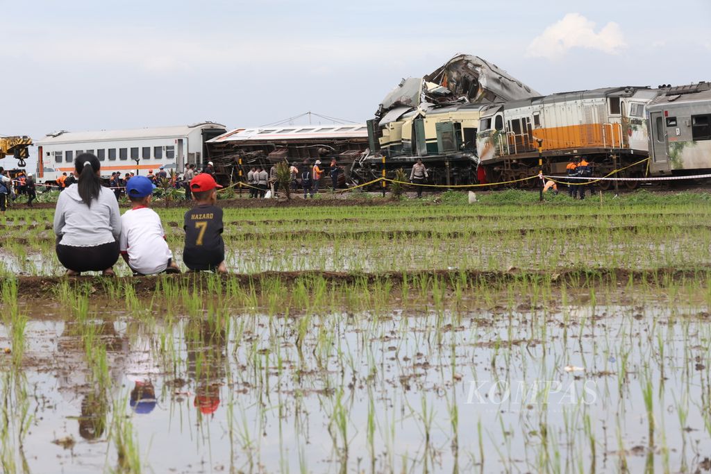 Warga menonton proses penanganan tabrakan Kereta Api Turangga relasi Surabaya Gubeng-Bandung dan Commuterline Bandung Raya di km 181+700 petak jalan antara Stasiun Haurpugur dan Stasiun Cicalengka, Jumat (5/1/2024).