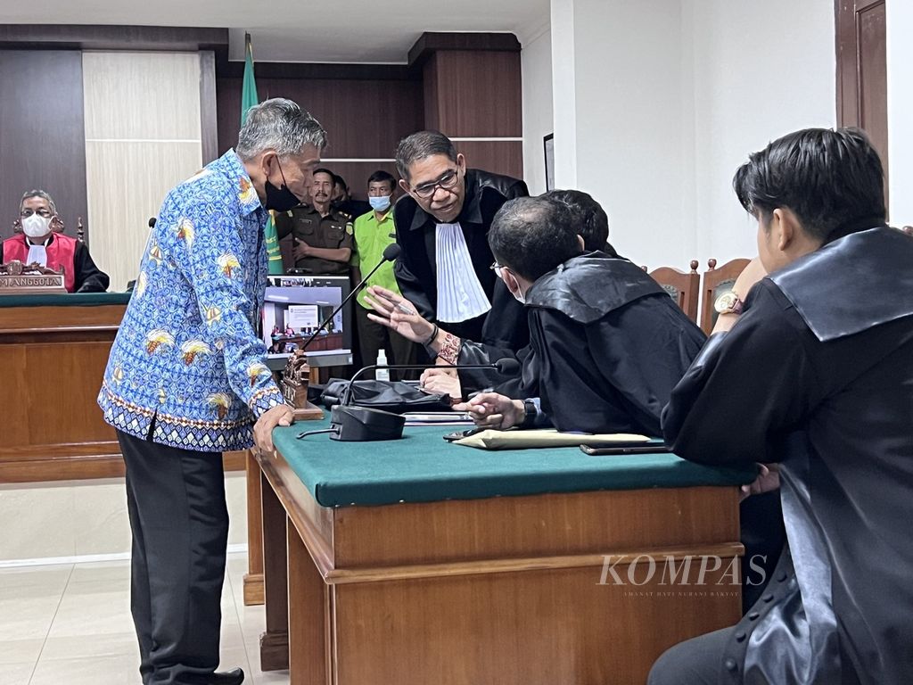 Terdakwa kasus pelanggaran HAM berat Paniai, Mayor Inf (Purn) Isak Sattu, berdiskusi dengan pengacaranya seusai pembacaan dakwaan di Pengadilan Negeri Makassar, Sulawesi Selatan, Rabu (21/9/2022).