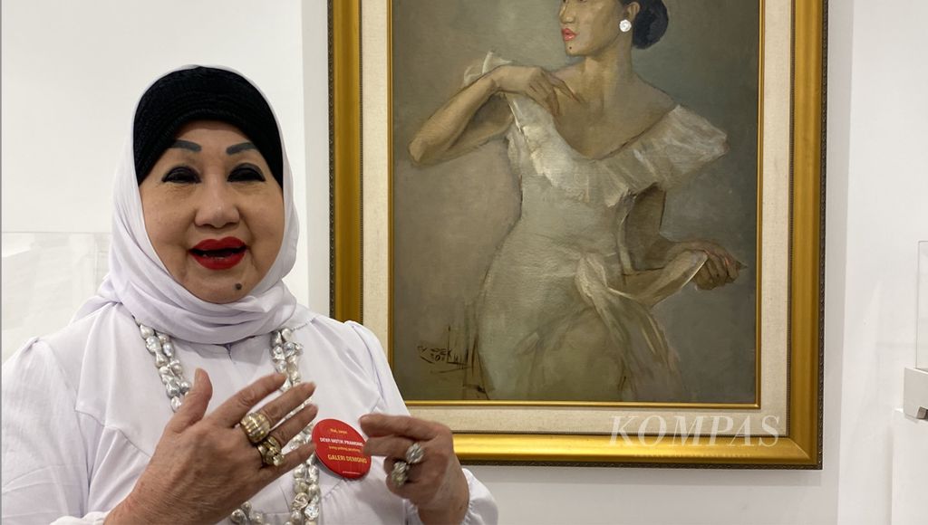 Dewi Motik (75) during the opening of the Demono gallery in Jakarta, Wednesday (08/05/2024). The oil painting behind Dewi is the work of Basuki Abdullah depicting Dewi's figure prior to her marriage in 1975. The Maestro titled the painting "The Last Virgin".