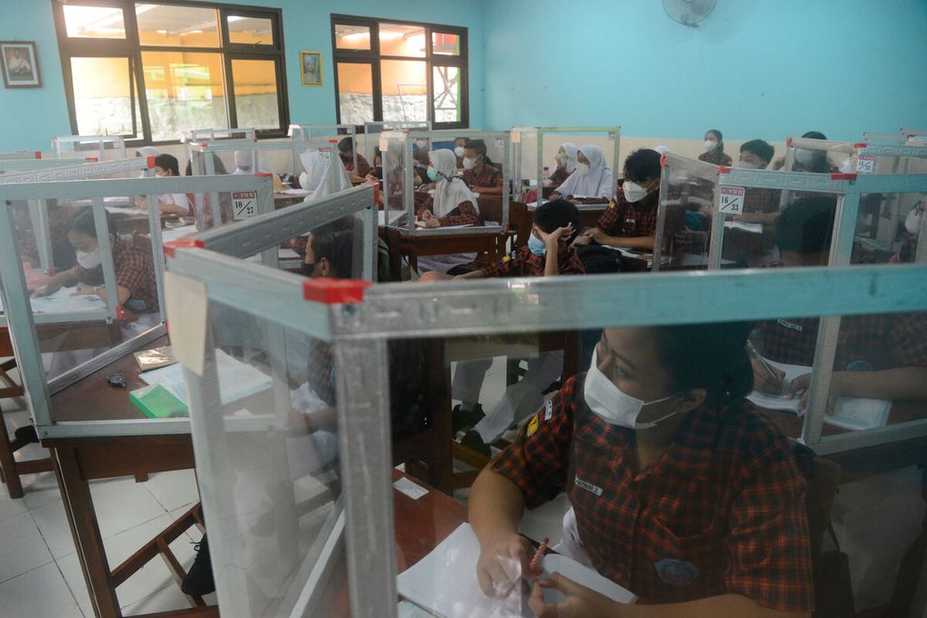 Siswa belajar dengan pembatas khusus di dalam kelas saat pembelajaran tatap muka dilakukan kembali secara penuh di SMP Negeri 5, Kota Semarang, Jawa Tengah, Rabu (12/1/2022).