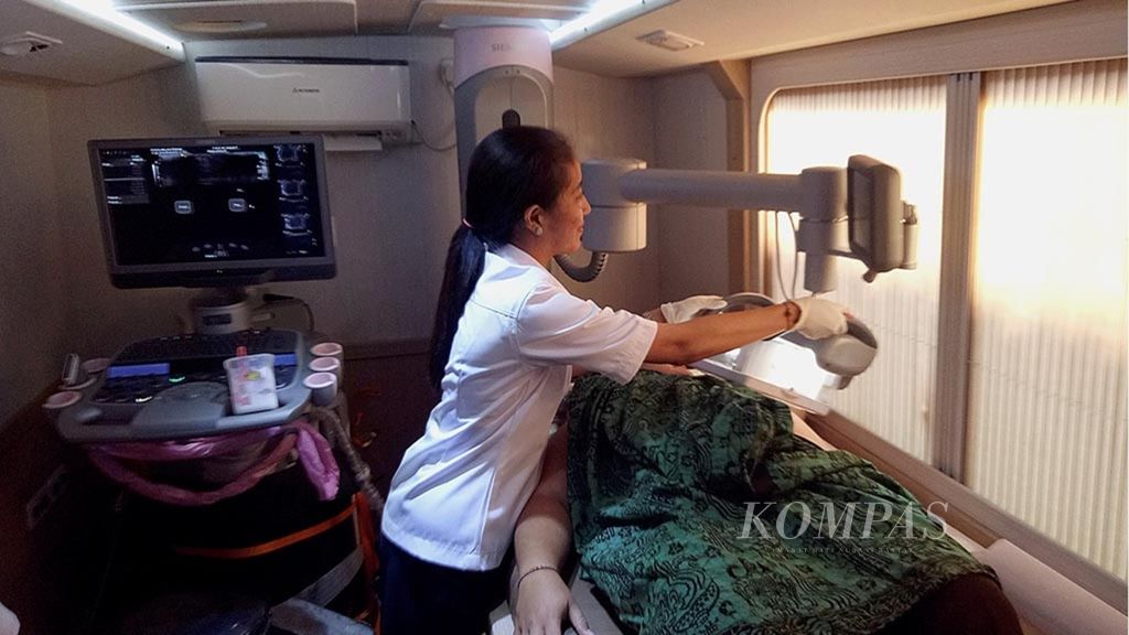 Seorang petugas medis dari Dinas Kesehatan Kabupaten Badung, Bali, memeriksa seorang ibu dengan alat deteksi kanker payudara, di atas bus pelayanan kesehatan gratis, di halaman Pura Desa lan Puseh Desa Kapal, 19 April 2017. Ini merupakan bagian dari komitmen Pemerintah Kabupaten Badung memberikan pelayanan maksimal untuk Progam Kesehatan Perempuan Badung. 