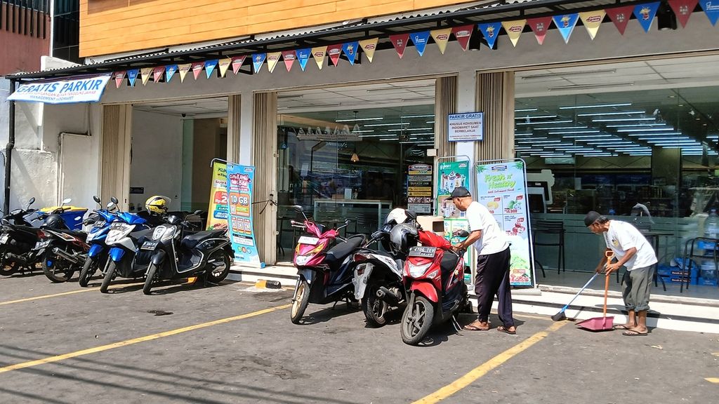 Soleh (54), juru parkir di minimarket di Kelapa Dua, Kebon Jeruk, Jakarta Barat, Sabtu (23/10/2023) siang, sedang merapikan kendaraan pelanggan. Meski di minimarket itu tertulis parkir gratis, Soleh dan temannya masih tetap bertahan.