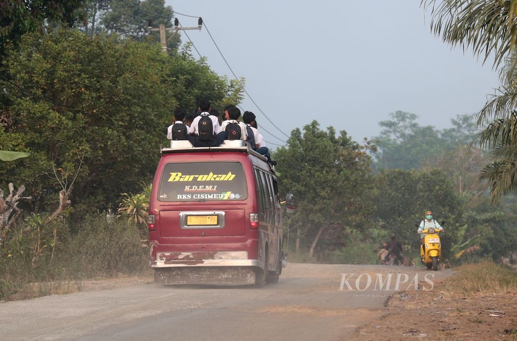 Anak-anak sekolah menumpang di atap mobil angkutan umum saat berangkat sekolah di kawasan Jalupang Mulya, Lebak, Banten, Selasa (19/9/2023). 