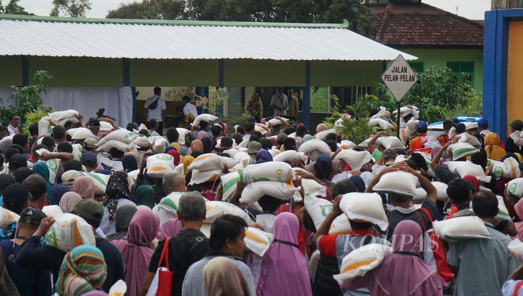 Warga berbondong-bondong keluar setelah mendapatkan bantuan pangan, di Gudang Bulog Meger, Kabupaten Klaten, Jawa Tengah, Rabu (31/1/2024). 