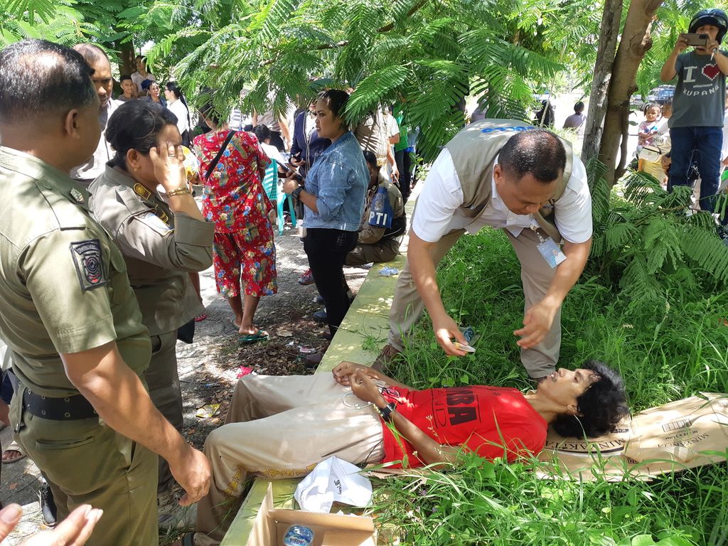 Seorang pria pingsan saat mengantre dalam kegiatan operasi pasar yang digelar Perum Bulog di Kota Kupang, Nusa Tenggara Timur pada Senin (13/3/2023). Pria itu diduga kelelahan saat  mengantre .