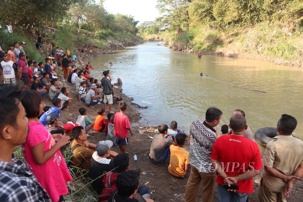 Warga menyaksikan proses pencarian korban tenggelam di Sungai Cimanis, Kabupaten Cirebon, Jabar, Selasa (5/7/2022).
