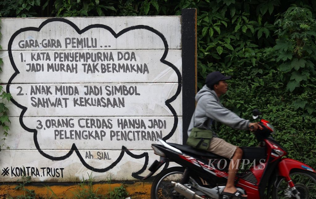 Warga melintas di dekat mural bertema Pemilu 2024 di kawasan Setu, Tangerang Selatan, Banten, Minggu (28/1/2024). 
