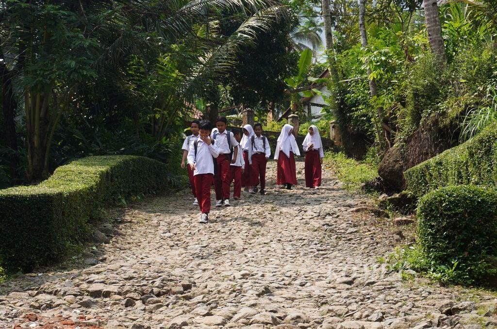 Siswa berjalan melewati jalanan rusak akibat tanah bergerak dalam menuju sekolah mereka di Madrasah Ibtidaiyah Pasawahan, Kecamatan Banjaranyar, Kabupaten Ciamis, Jawa Barat, Selasa (19/7/2022). 