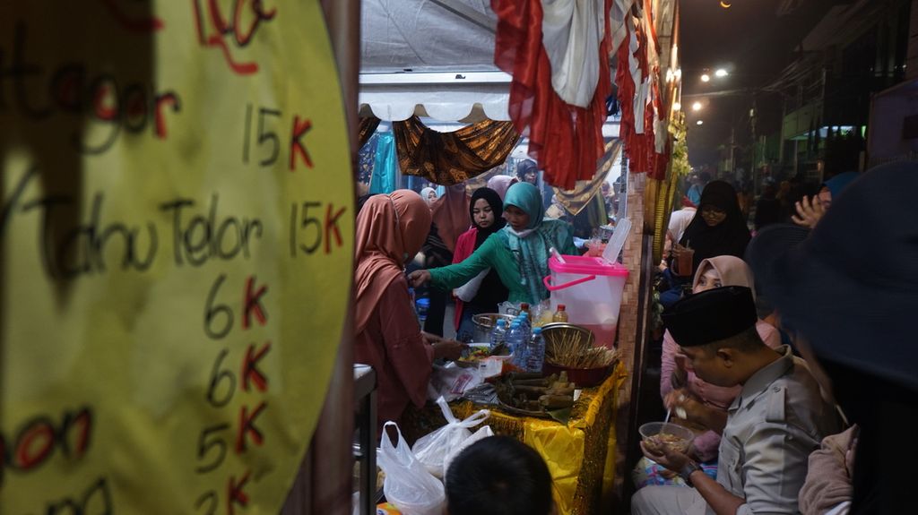 Pengunjung menikmati jajanan di stan usaha mikro kecil menengah (UMKM) dalam pasar rakyat Festival Peneleh di Jalan Makam Peneleh, Surabaya, Jawa Timur, Jumat (7/7/2023) malam. 