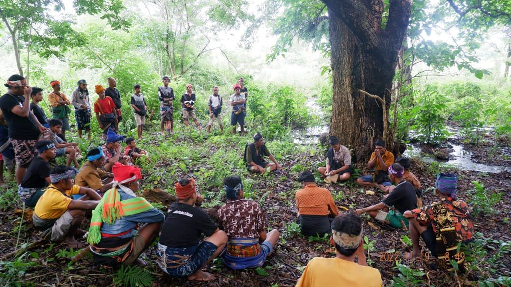 Masyarakat adat Sumba atau para Kabihu duduk membentuk lingkaran di dekat sebuah pohon relatif besar dengan sungai yang sedang mengalir di dekatnya. Pohon dan sumber air ini harus dijaga dan dirawat melalui kesepakatan adat bersama dalam festival "Humba" IX di Lewa, Sumba Timur, Senin (21/11/2022). Masyarakat adat menjadi pengawal hutan dan sumber mata air untuk kehidupan yang berkelanjutan.