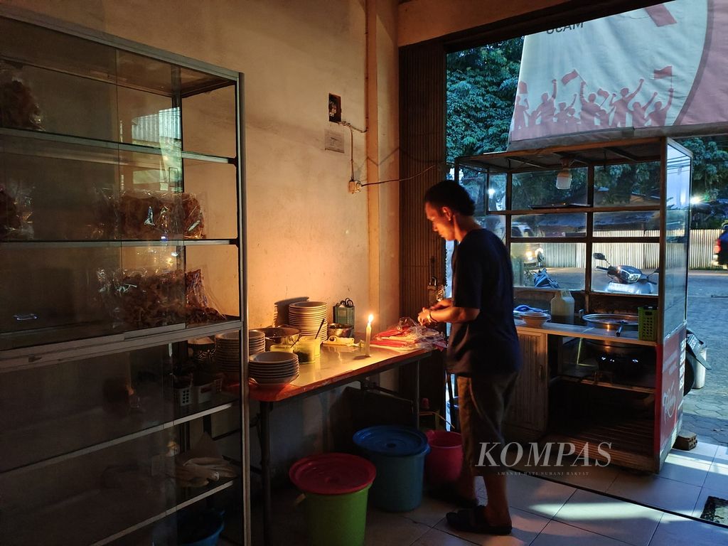 Karyawan bekerja menggunakan lilin di Warung Model Haji Dowa di Kelurahan Bukit Sangkal, Kecamatan Kalidoni, Palembang, Sumatera Selatan, Selasa (4/6/2024) pukul 18.30. 