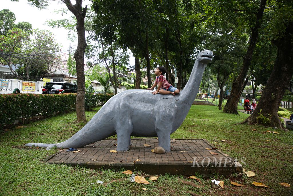 Seorang anak menaiki patung dinosaurus di Taman Situ Lembang, Menteng, Jakarta Pusat yang ramai dikunjungi warga Minggu (26/12/2021). 