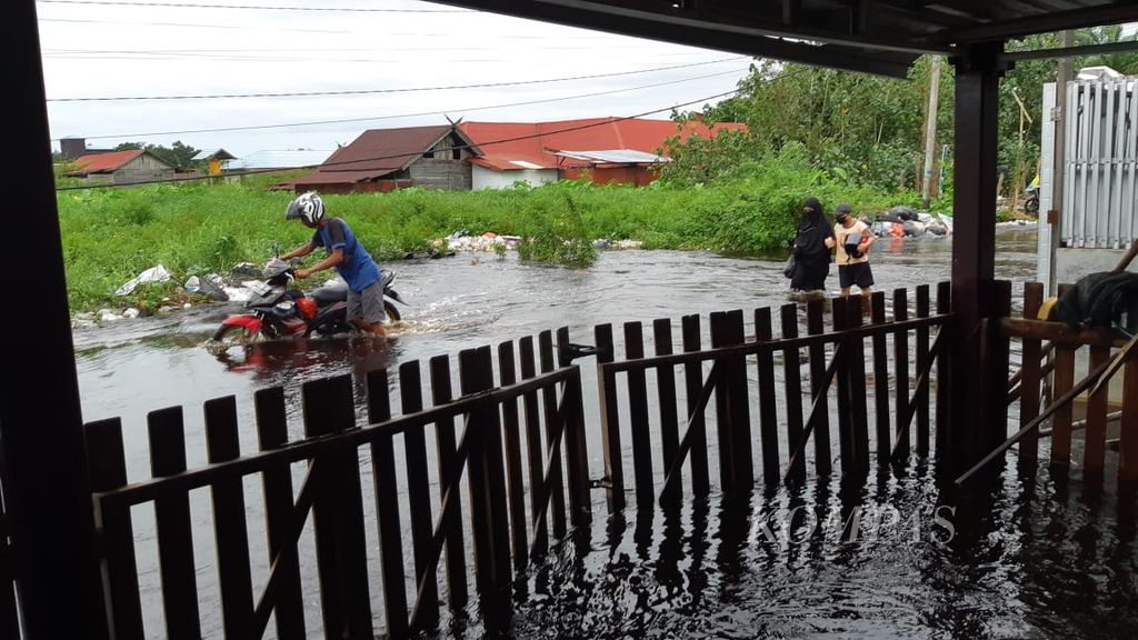 Warga Kelurahan Palangka, Kota Palangkaraya, Kalimantan Tengah, melintas di tengah banjir di Jalan Arut, Kota Palangkaraya, Minggu (10/3/2024).