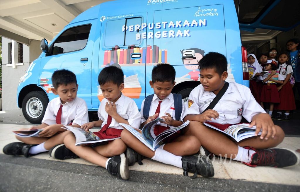 Anak membaca buku saat berlangsung penyerahan Mobil Perpustakaan Keliling <i>Kompas </i>Gramedia kepada Pemerintah Kota Surabaya di halaman Pemkot Surabaya, Senin (28/5/2018). 