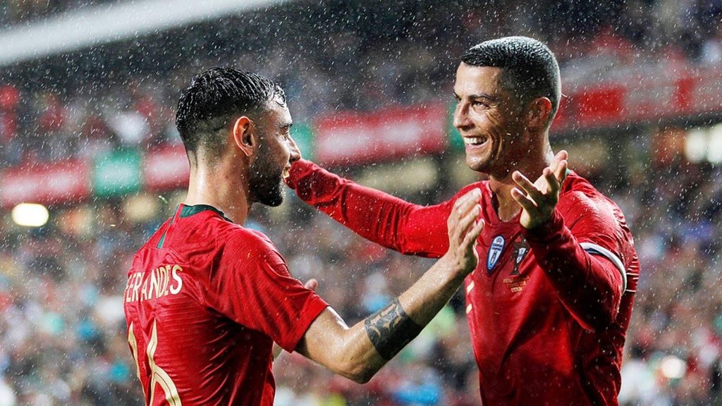 Gelandang Portugal, Bruno Fernandes (kiri), bergembira bersama rekannya, Cristiano Ronaldo, seusai Bruno mencetak gol kedua pada laga persahabatan melawan Aljazair, Kamis (7/6/2018), di Estadio da Luz, Lisabon. Portugal memenangi laga kandang itu 3-0.