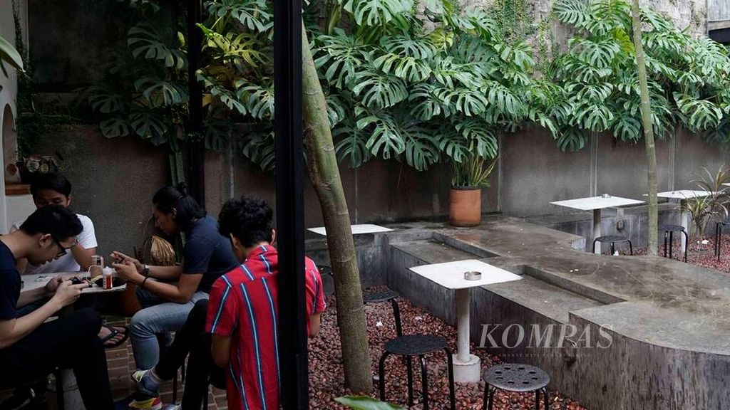 Hujan menembus ruang terbuka di kafe Kopi Kalyan di kawasan Barito, Jakarta Selatan, Selasa (7/1/2020). Kafe kini mulai berubah tidak saja sebagai tempat makan dan minum, <i>nongkrong</i> dan bertemu relasi. Namun, juga sebagai tempat bekerja dengan suasana yang mendukung dan tempat bagi seniman untuk memamerkan karya.