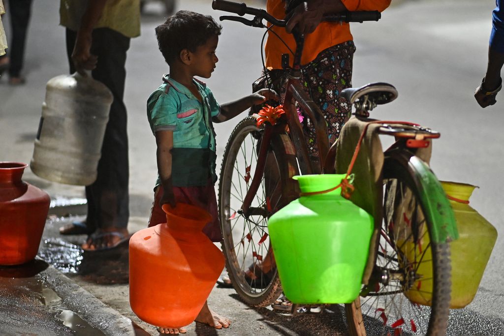 Seorang anak laki-laki memegang tempayan untuk mengisi air di tengah krisis air yang sedang berlangsung di Bengaluru, India, 14 Maret 2024.