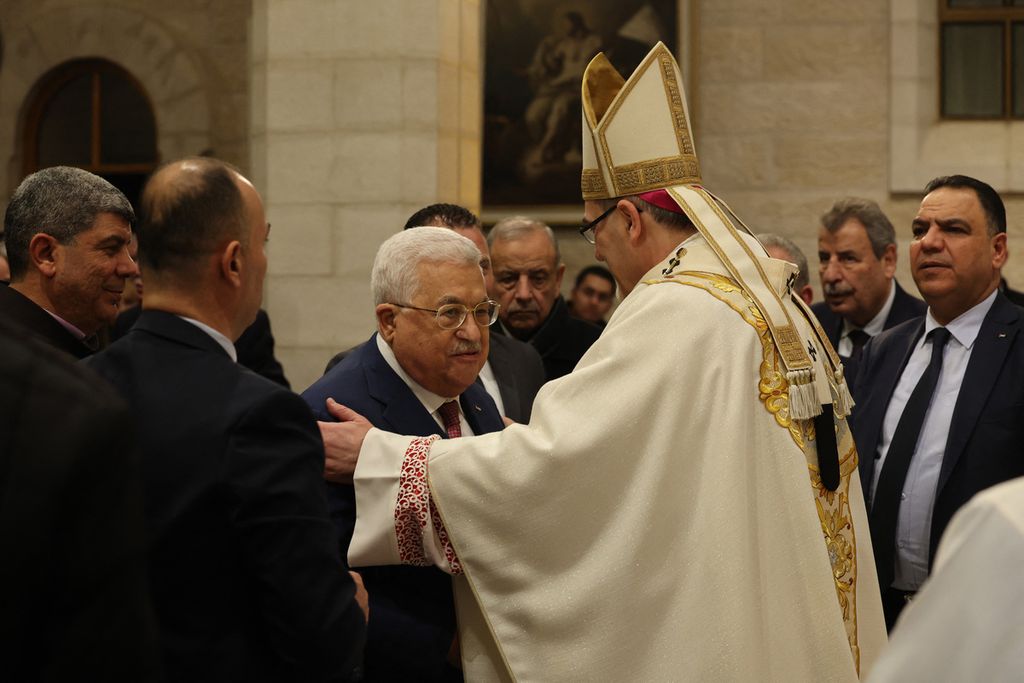 Presiden Palestina Mahmoud Abbas (tiga dari kiri) disambut Uskus Agung Jerusalem Pierbattista Pizzaballa menjelang misa malam Natal di Gereja Kelahiran, Minggu (25/12/2022), di Bethlehem, Palestina, Gereja itu dibangun di lokasi yang diyakini sebagai tempat kelahiran Yesus