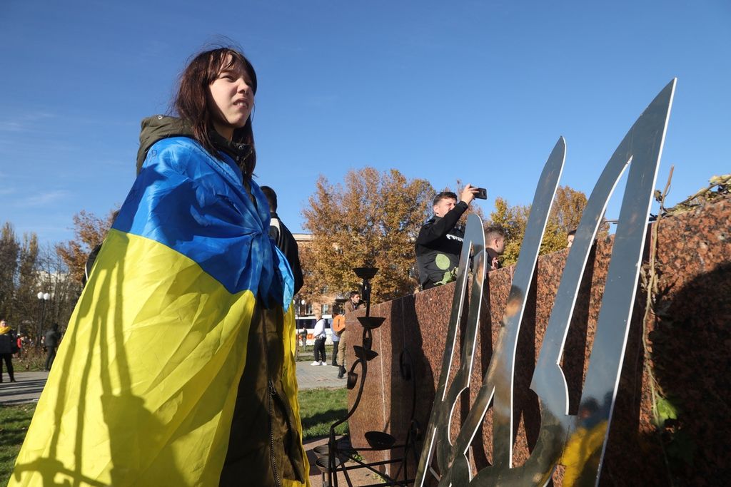 Seorang gadis menyelimuti tubuhnya dengan bendera Ukraina, menyiratkan kegembiraannya setelah Kota Kherson berhasil diambil alih oleh militer Ukraina(14/11/2022). 