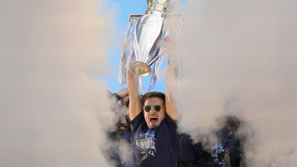 Pemain Manchester City, Jack Grealish, mengangkat trofi juara dalam perayaan kesuksesan tim itu menjadi kampiun Liga Inggris musim 2021-2022, Senin 23 Mei 2022. 