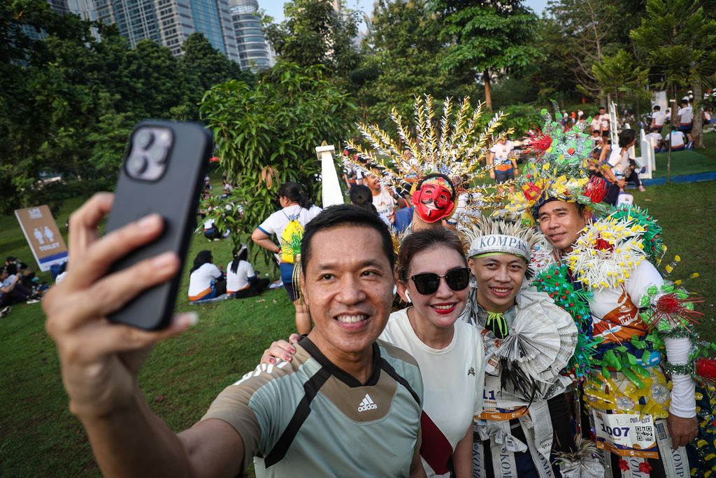 Tiga peserta berkostum unik berswafoto dalam acara Run The City di Hutan Kota Gelora Bung Karno, Jakarta, Sabtu (1/7/2023). 
