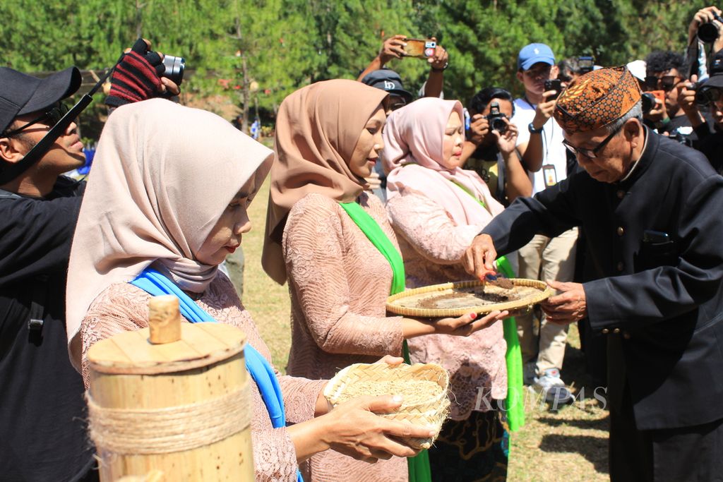 Tokoh masyarakat (kanan) melakukan prosesi &quot;nitip bibit pelak tanceb&quot; dalam Sedekah Bumi di Desa Cibuntu, Kecamatan Pasawahan, Kabupaten Kuningan, Jawa Barat, Sabtu (7/9/2024). Prosesi itu menyimbolkan penyerahan benih padi agar mendapatkan hasil panen yang melimpah.