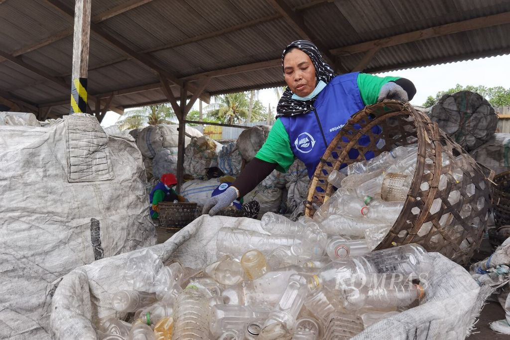 Suriah memasukkan botol plastik yang telah ia sortir ke dalam karung untuk selanjutnya digiling di Unit Bisnis Daur Ulang atau Lombok PET di Lombok Barat, Nusa Tenggara Barat, Kamis (9/2/2023).