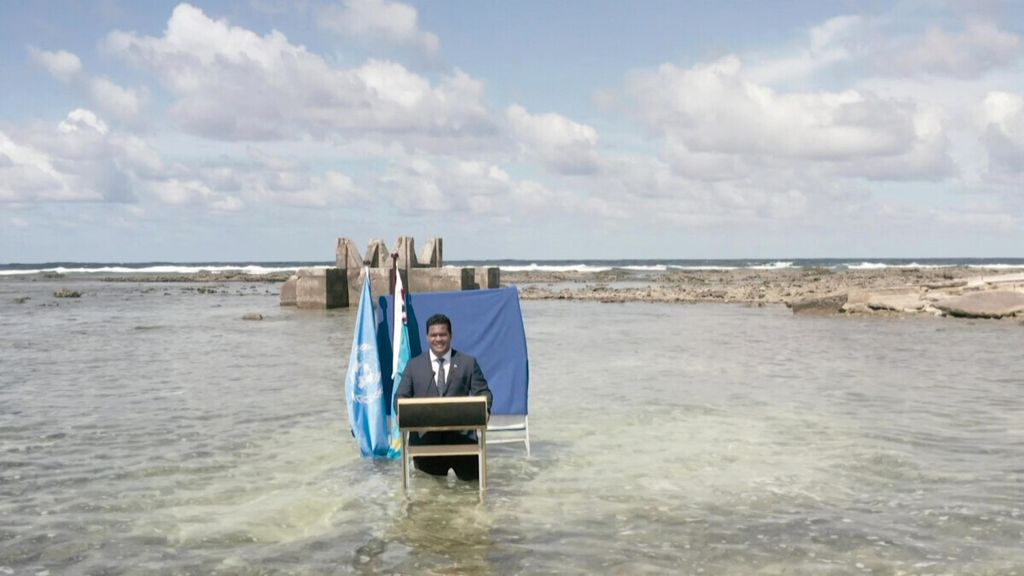 Foto yang diambil dari rekaman video yang dirilis Kementerian Kehakiman dan Luar Negeri Tuvalu pada 9 November 2021 ini menunjukkan Menlu Tuvalu Simon Kofe berdiri setinggi 50 cm di perairan lepas pantai Tuvalu ketika ia berbicara kepada para delegasi di COP26 PBB yang sedang berlangsung Konferensi Perubahan Iklim di Glasgow, Skotlandia.