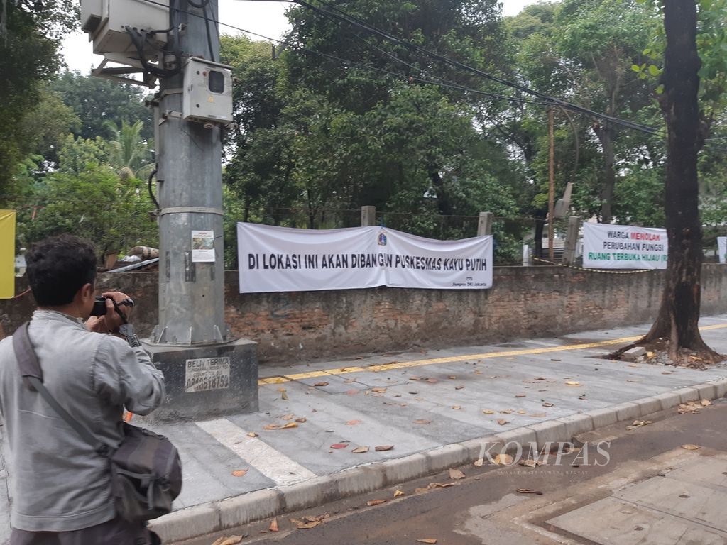 Spanduk penolakan warga yang dipajang di tembok ruang terbuka hijau (RTH) yang dijebol oleh jajaran Kelurahan Kayu Putih, Kecamatan Pulogadung, Kota Jakarta Timur, Jumat (24/11/2023). 