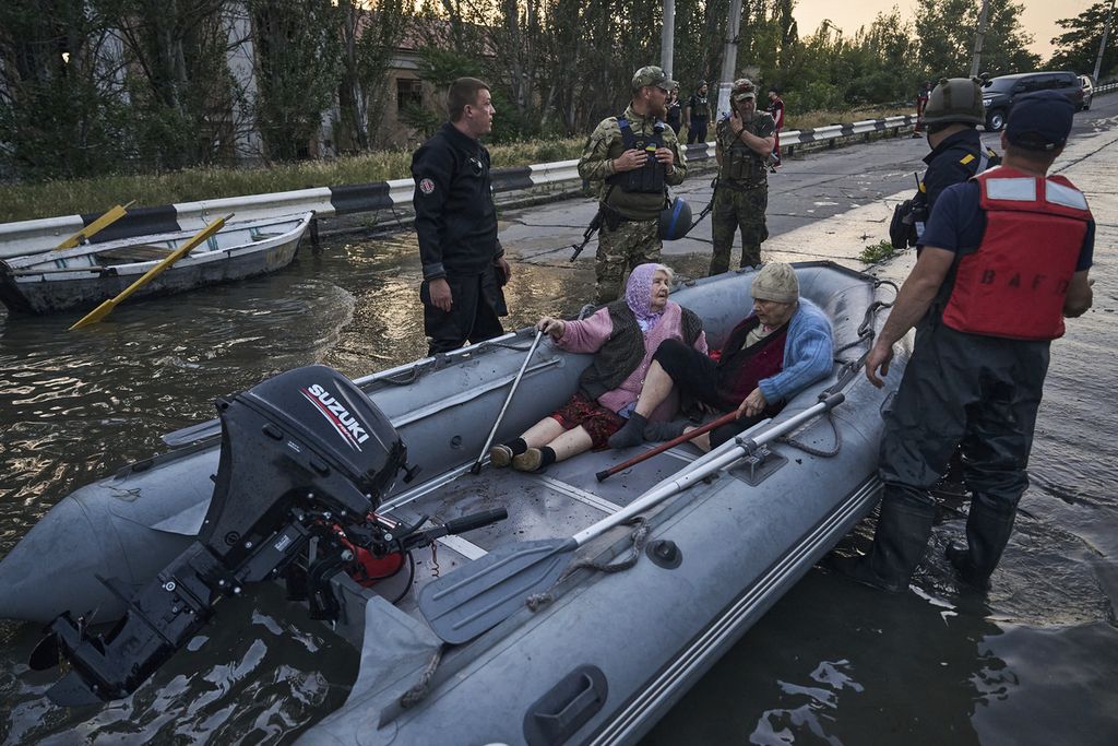 Petugas penyelamat berusaha menarik perahu yang mengangkut warga untuk dievakuasi dari wilayah banjir di Kherson, Ukraina, Selasa (6/6/2023). 