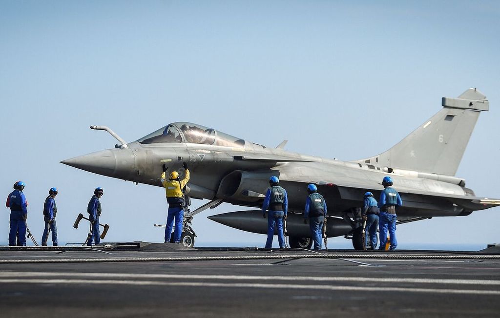 Foto 5 Juni 2021 ini memperlihatkan para awak berdiri di dekat jet tempur Rafale di dek kapal induk Perancis, Charles-de-Gaulle, di lepas pantai Toulon, Perancis. 