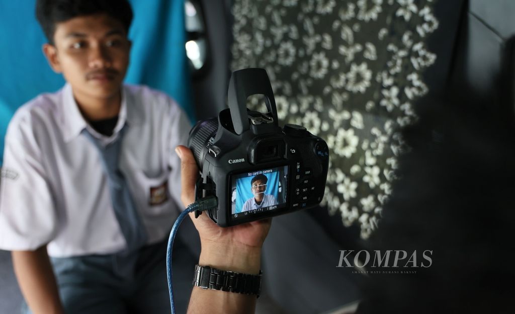 Petugas mengambil foto siswa kelas XI saat perekaman data untuk pembuatan kartu tanda penduduk elektronik atau KTP-el di SMAN 2 Kota Tangerang, Banten, Senin (13/11/2023). 