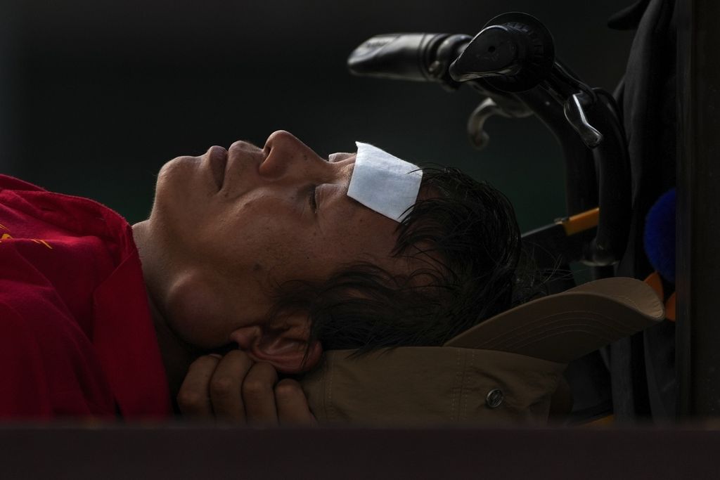 Seorang laki-laki dengan bantalan pendingin di dahinya sedang tidur siang di bangku pada hari yang terik di Beijing, China, 24 Juli 2023. 