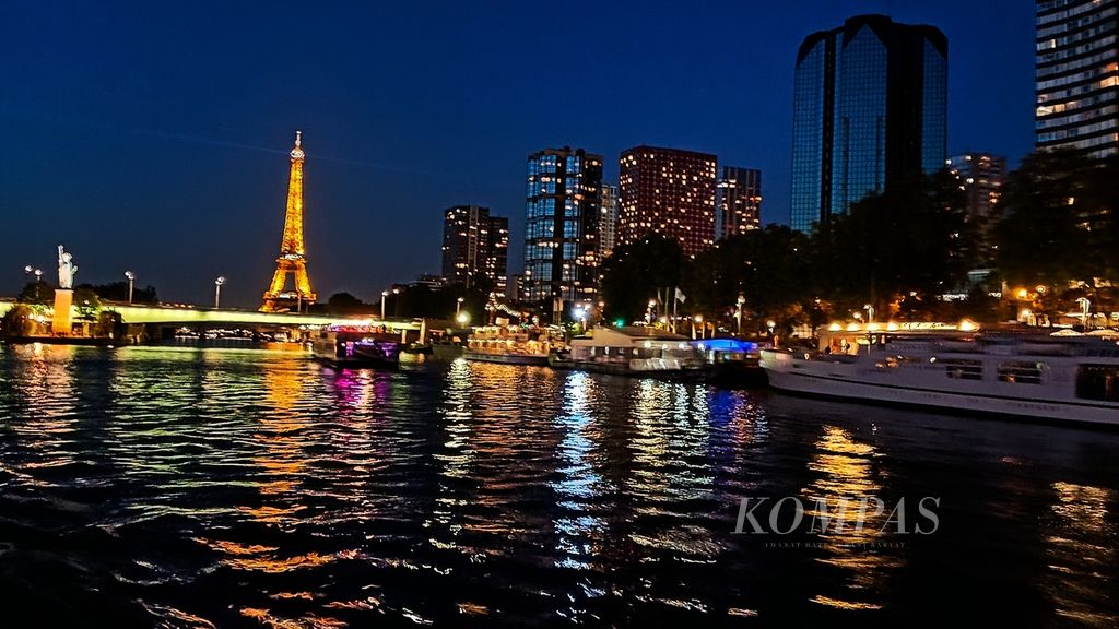 Suasana malam di kota Paris dari atas perahu wisata Bateau Parisien yang membawa wisatawan menyusuri Sungai Seine, Selasa (18/7/2023). Tampak dari kejauhan cahaya lampu Menara Eiffel.