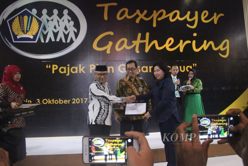 Sekretaris Daerah Provinsi Kalimantan Selatan Abdul Haris Makkie (kedua dari kiri) memberikan piagam penghargaan kepada pengusaha yang patuh membayar pajak dalam acara Taxpayer Gathering 2017 di Grand Palace Ballroom, Banjarmasin, Oktober 2017.
