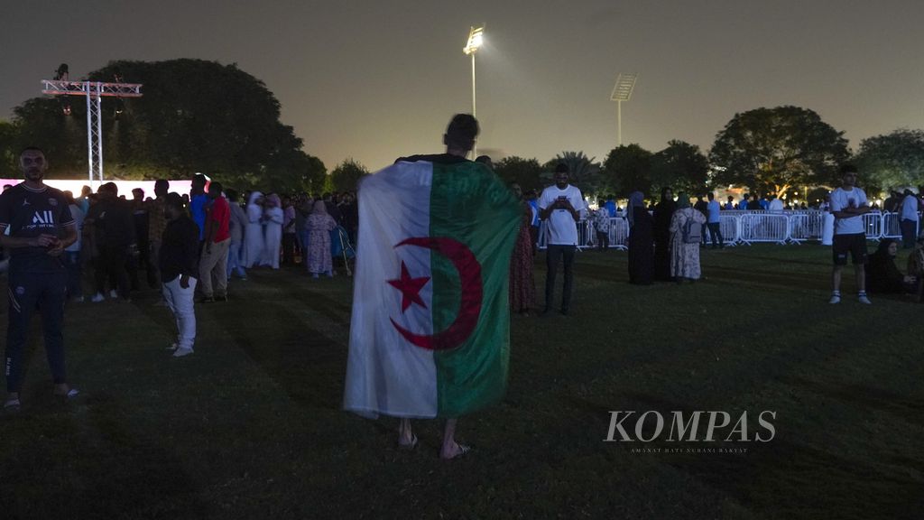 Seorang pria membawa bendera Aljazair dalam acara tur trofi Piala Dunia yang dipamerkan di Aspire Park, Doha, Qatar, Selasa (15/11/2022). Ajang ini menjadi penyemarak menjelang diselenggarakan turnamen Piala Dunia 2022 yang akan berlangsung 20 November - 18 Desember 2022. 