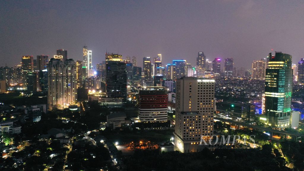 Lampu penerangan menyala menjelang malam di gedung bertingkat di kawasan Kuningan, Jakarta Selatan, Minggu (31/7/2022). 